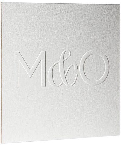 A white blind embossed card with the letters "M & O"